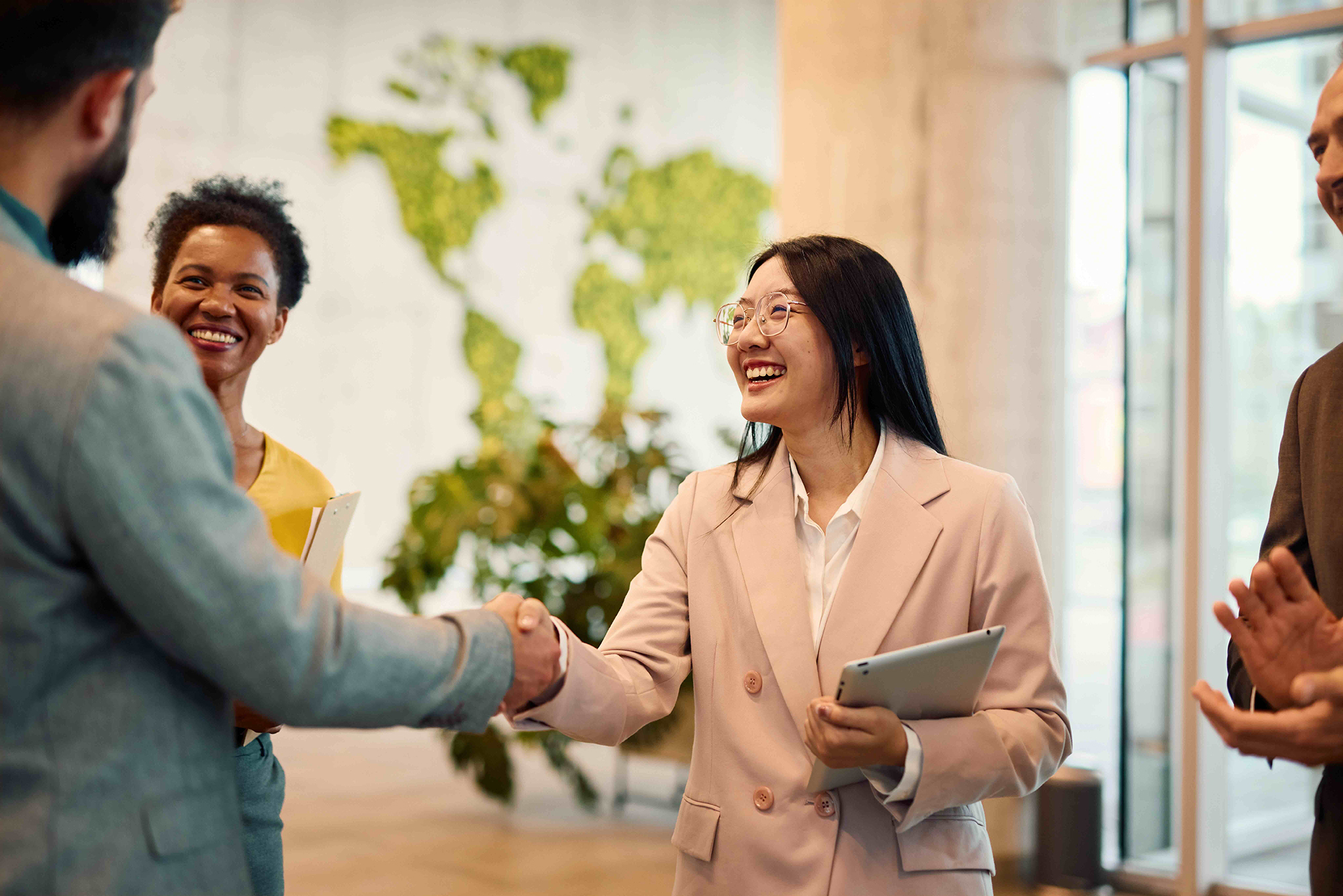 Drei Personen stehen zusammen und geben sich die Hand in einem Büro.