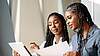 Two women sitting together, looking at a document.
