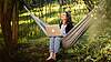 bild Woman sitting relaxed in a hammock outdoors and working on her laptop.