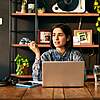 Young woman sitting with a laptop at a wooden table in a modern room.