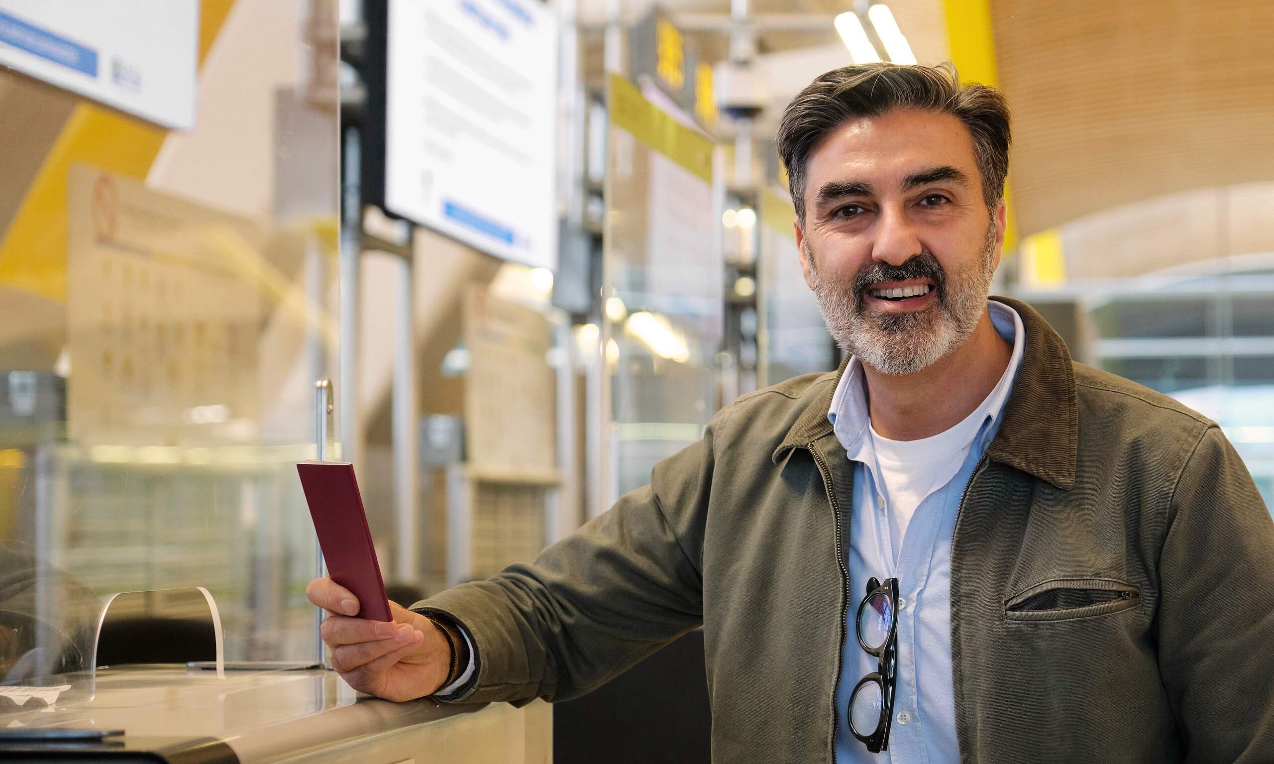 Lächelnder Mann steht in einem modernen Büro mit bunten Akzenten.