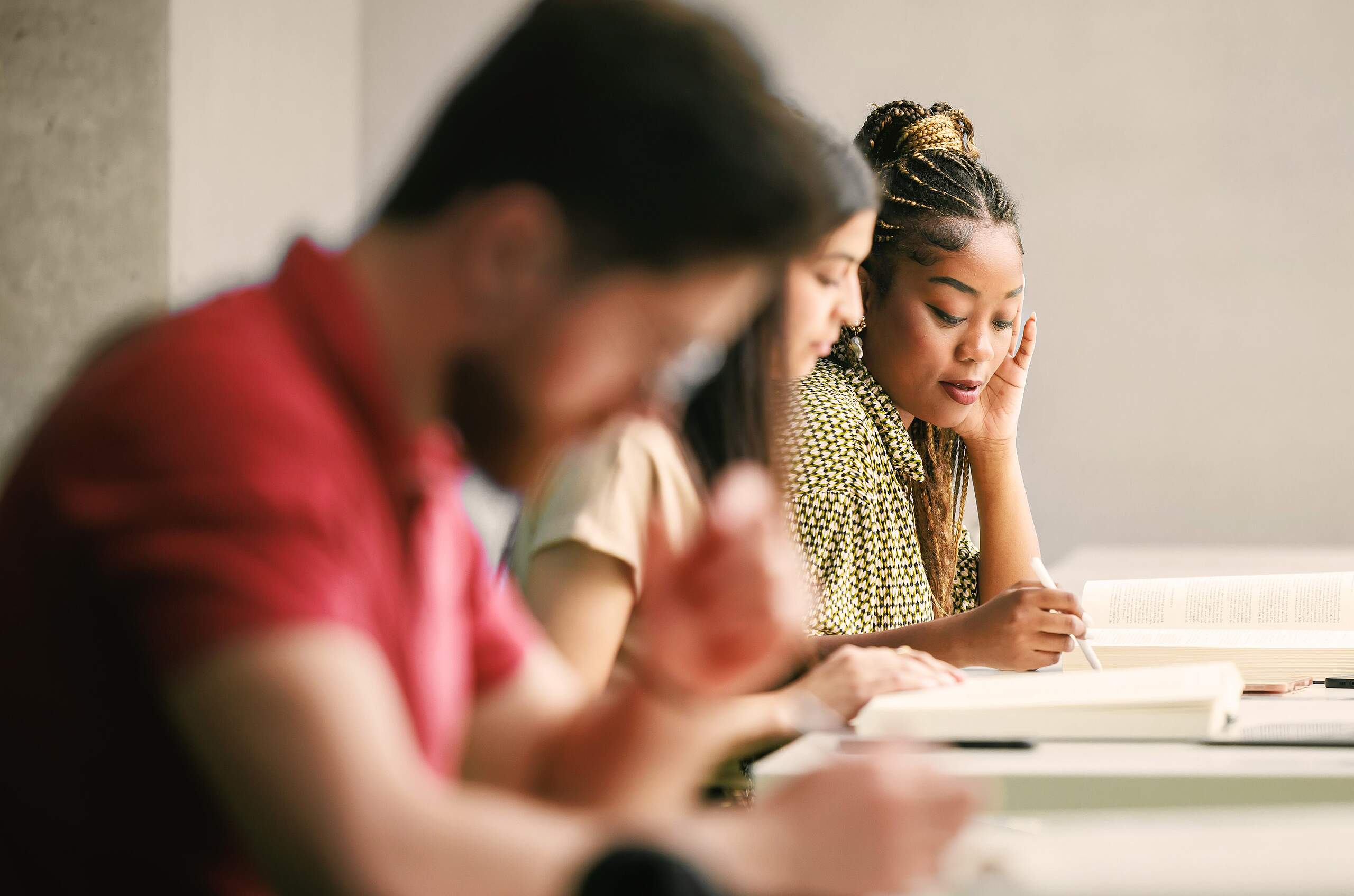 Gruppe von Personen sitzt an einem Tisch und arbeitet gemeinsam mit Dokumenten.